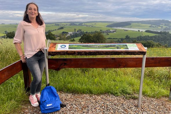 Vanessa Greven vom Tourist-Info Burg-Reuland an der Panoramatafel auf dem Leichenweg zwischen Weweler und Lascheid