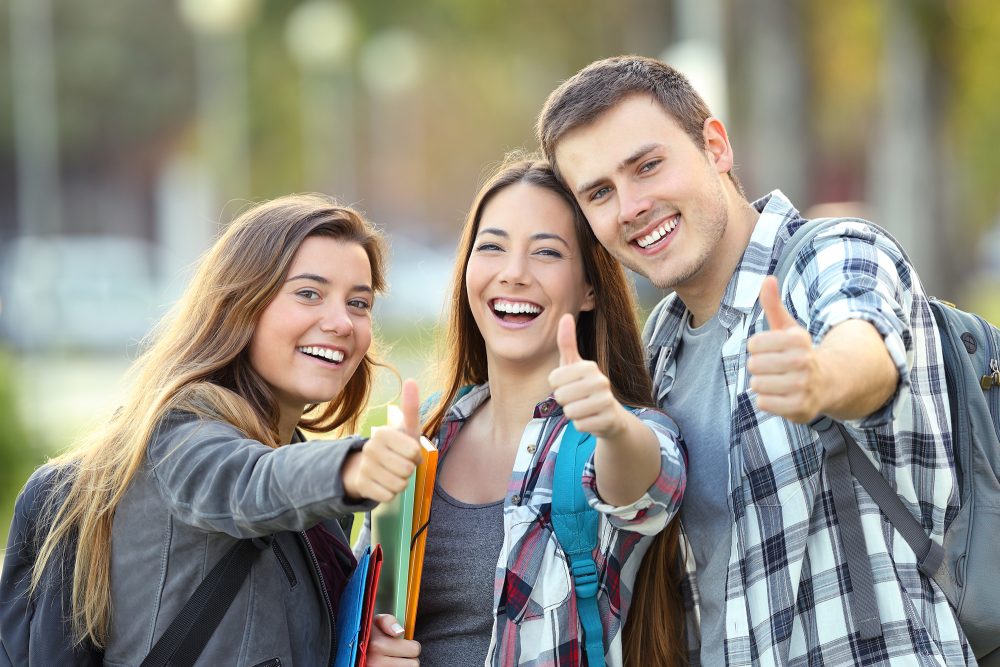 Drei glückliche Schüler mit Daumen hoch