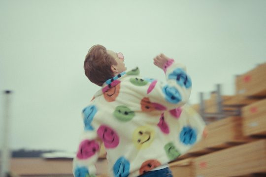 Marius Lerho ist von hinten zu sehen in einer Jacke mit vielen bunten Smileys drauf