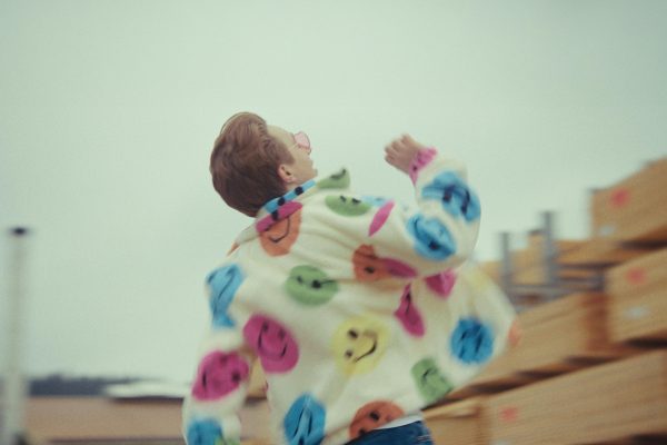 Marius Lerho ist von hinten zu sehen in einer Jacke mit vielen bunten Smileys drauf