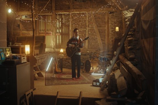 Marius Lerho mit seiner Gitarre in einem alten Stall