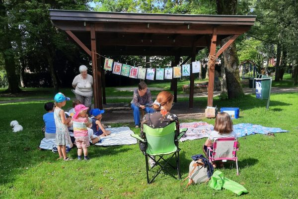 Lesen im Park: Vorleserin mit einigen Kindern