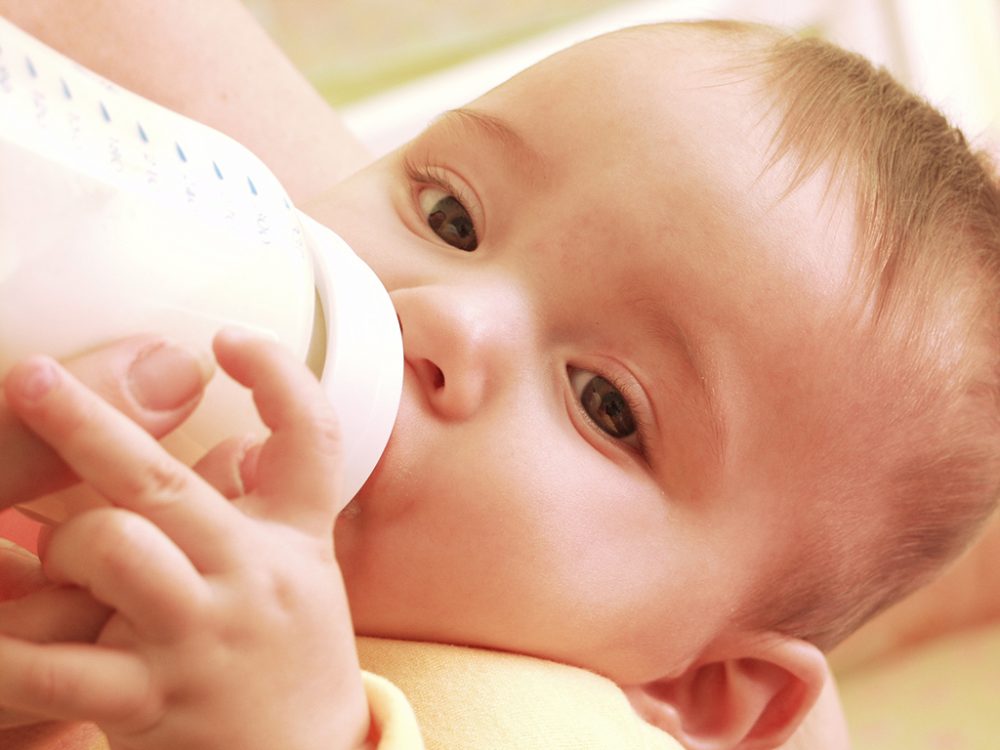 Mutter füttert ihren kleinen Jungen mit einer Babyflasche