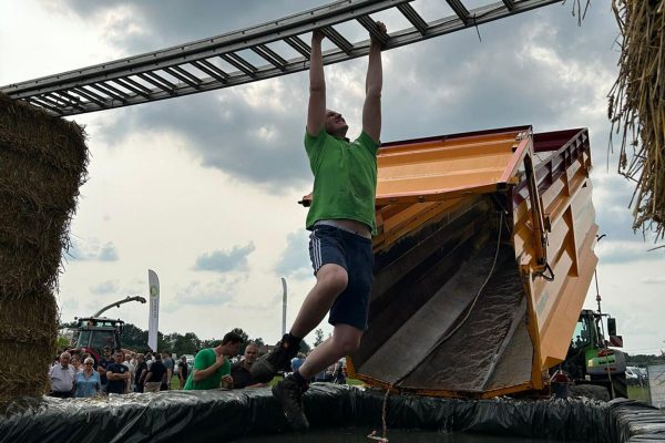 Ein Teilnehmer der Aktion "Held vom Feld" hangelt an einer Leiter über ein Güllebecken