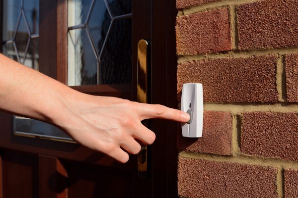 Weibliche Hand drückt auf einen Klingelknopf
