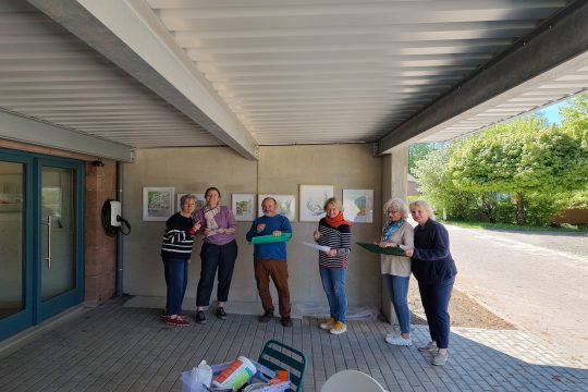 Sechs der neun Mitglieder der Künstlergruppe stehen vor einigen Werken