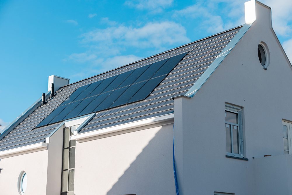 Neu gebautes Haus in den Niederlanden mit Sonnenkollektoren auf dem Dach vor einem sonnigen Himmel