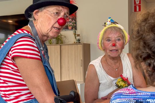 Zwei Cliniclowns im Gespräch mit einer Bewohnerin, die von hinten im Bild ist